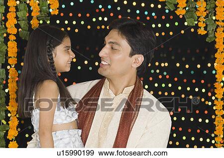 Close-up of a young man carrying his daughter View Large Photo Image Stock Photo - Close-up of a young man carrying his daughter. Fotosearch