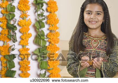 Stock Photograph - Portrait of a girl holding a diwali lamp and smiling. Fotosearch