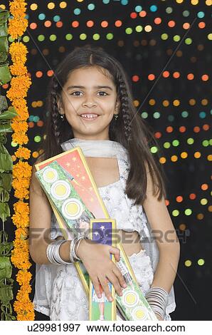 Stock Photo - Portrait of a girl holding diwali crackers. Fotosearch