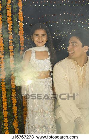 Portrait of a girl lighting a sparkler with her father sitting beside her View Large Photo Image Stock Image - Portrait of a girl lighting a sparkler with her father sitting beside her. Fotosearch