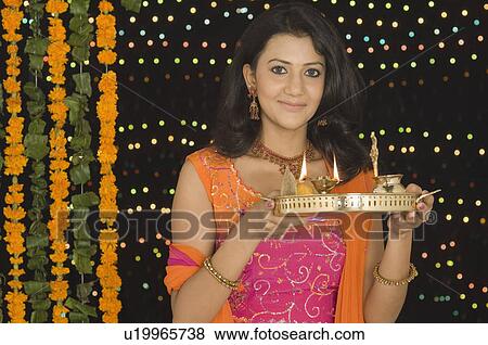 Portrait of a young woman holding a diwali thali View Large Photo Image Stock Photo - Portrait of a young woman holding a diwali thali. Fotosearch