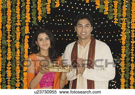 Portrait of a young woman holding a diwali thali with a young man standing beside her View Large Photo Image Stock Photography - Portrait of a young woman holding a diwali thali with a young man standing beside her. Fotosearch