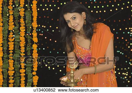 Portrait of a young woman lighting a lamp View Large Photo Image Stock Image - Portrait of a young woman lighting a lamp. Fotosearch