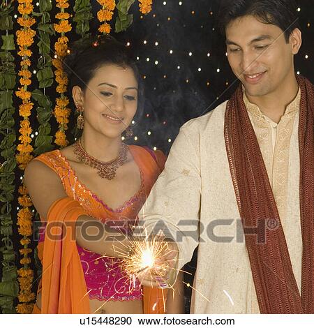 Stock Image - Young couple holding a sparkler. Fotosearch