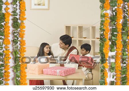 Young man sitting with his son and daughter and holding gifts View Large Photo Image Stock Image - Young man sitting with his son and daughter and holding gifts. Fotosearch