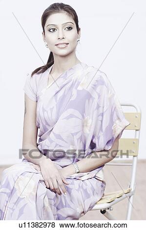 Close-up of a young woman sitting on a chair View Large Photo Image Stock Photo - Close-up of a young woman sitting on a chair. Fotosearch