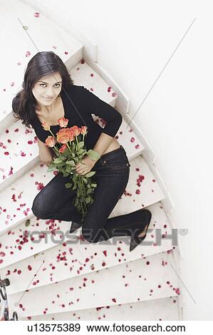 Stock Photo - High angle view of a young woman holding a bouquet of flowers. Fotosearch