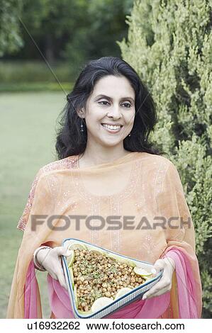 Stock Image - Mid adult woman holding a dish of sliced vegetables. Fotosearch