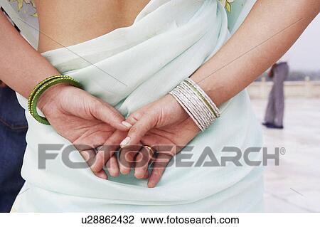 Mid section view of a young woman with her hands behind her back View Large Photo Image Stock Image - Mid section view of a young woman with her hands behind her back. Fotosearch