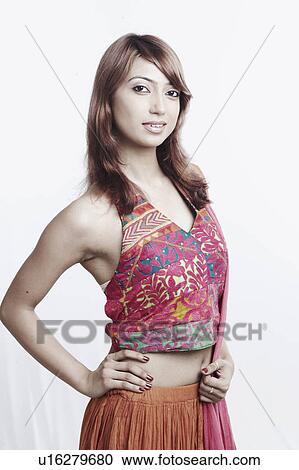 Stock Image - Portrait of a young woman standing with arms akimbo. Fotosearch