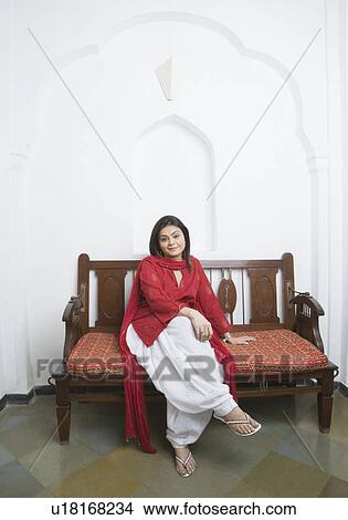 Picture - Portrait of a mid adult woman sitting on a couch and smiling. Fotosearch