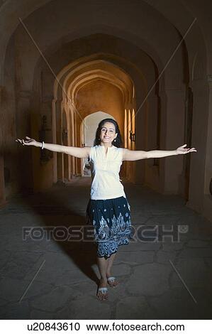 Stock Image - Portrait of a mid adult woman standing with her arms outstretched and smiling, Neemrana Fort Palace, Neemrana, Alwar, Rajasthan, India. Fotosearch