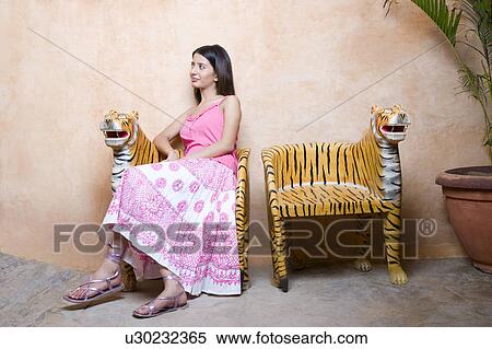 Young woman sitting on a chair View Large Photo Image Stock Photography - Young woman sitting on a chair. Fotosearch