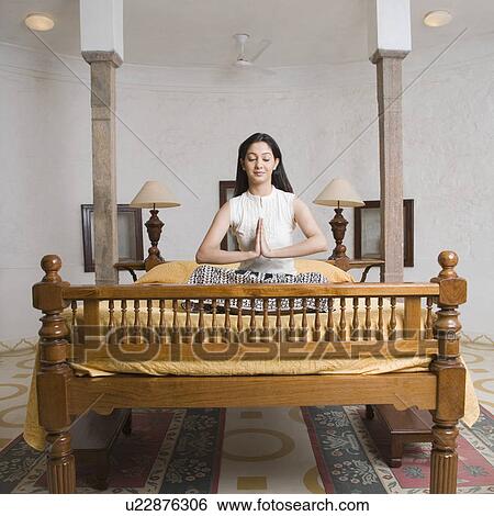 Young woman sitting on the bed in a prayer position View Large Photo Image Stock Photograph - Young woman sitting on the bed in a prayer position. Fotosearch