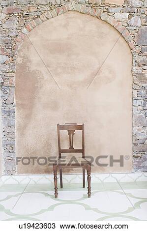 Stock Image - Empty chair in front of a wall. Fotosearch