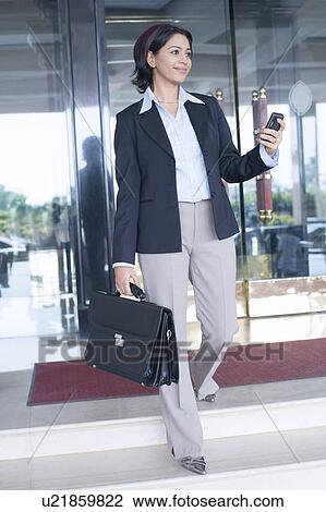 Businesswoman holding a bag and a mobile phone View Large Photo Image Stock Image - Businesswoman holding a bag and a mobile phone. Fotosearch