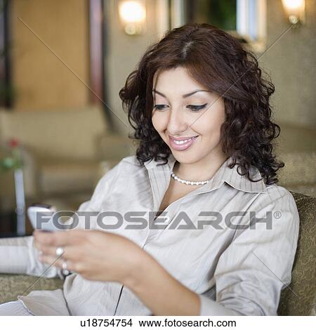 Businesswoman text messaging on a mobile phone and smiling View Large Photo Image Picture - Businesswoman text messaging on a mobile phone and smiling. Fotosearch