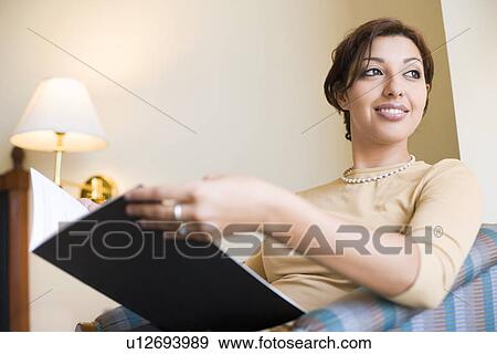 Stock Photo - Close-up of a businesswoman holding a file and smiling. Fotosearch