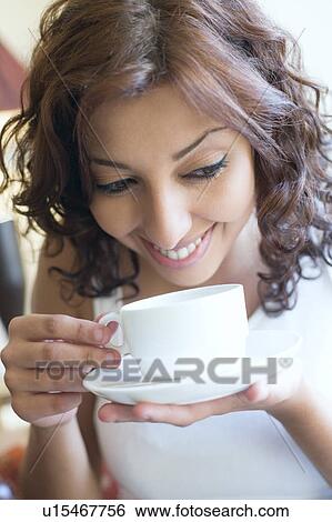 Close-up of a young woman drinking a cup of tea and smiling View Large Photo Image Stock Photograph - Close-up of a young woman drinking a cup of tea and smiling. Fotosearch