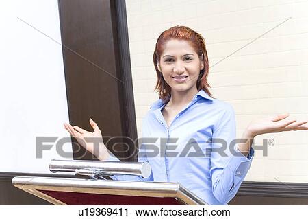 Stock Image - Portrait of a businesswoman giving speech at a lectern. Fotosearch