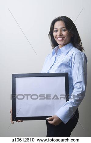 Portrait of a businesswoman holding a blank picture frame and smiling View Large Photo Image Stock Image - Portrait of a businesswoman holding a blank picture frame and smiling. Fotosearch