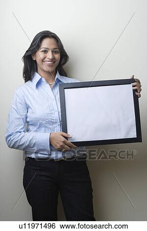Portrait of a businesswoman holding a blank picture frame and smiling View Large Photo Image Stock Photograph - Portrait of a businesswoman holding a blank picture frame and smiling. Fotosearch