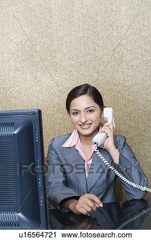 Stock Image - Portrait of a businesswoman talking on the telephone and smiling. Fotosearch