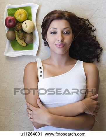 Portrait of a young woman lying near a fruit tray View Large Photo Image Stock Image - Portrait of a young woman lying near a fruit tray. Fotosearch