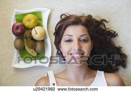 Portrait of a young woman smiling with a fruit tray beside her View Large Photo Image Stock Image - Portrait of a young woman smiling with a fruit tray beside her. Fotosearch