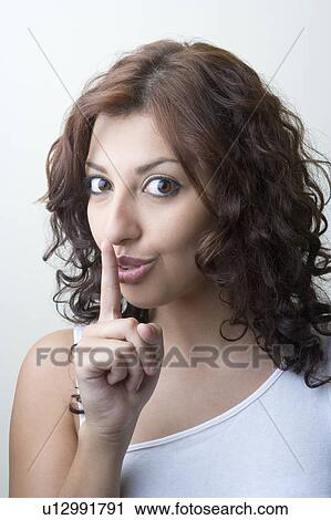 Portrait of a young woman with finger on her lips View Large Photo Image Stock Image - Portrait of a young woman with finger on her lips. Fotosearch