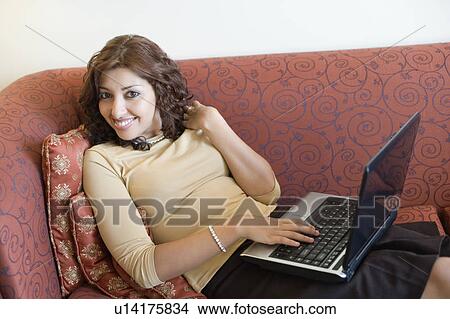 Picture - Portrait of a young woman working on a laptop and smiling. Fotosearch