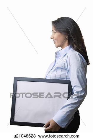 Side profile of a businesswoman holding a blank picture frame and smiling View Large Photo Image Stock Photo - Side profile of a businesswoman holding a blank picture frame and smiling. Fotosearch