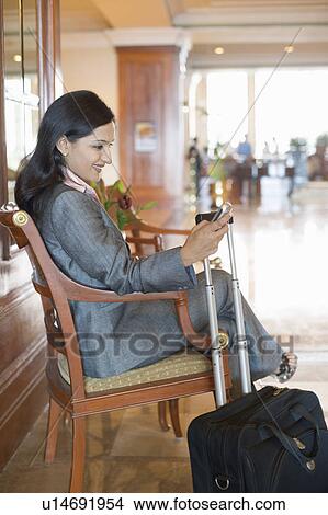Side profile of a businesswoman text messaging on a mobile phone and smiling View Large Photo Image Picture - Side profile of a businesswoman text messaging on a mobile phone and smiling. Fotosearch