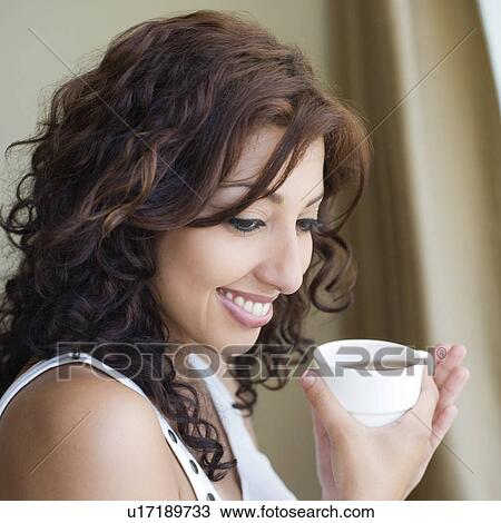 Side profile of a young woman holding a cup of tea and smiling View Large Photo Image Stock Image - Side profile of a young woman holding a cup of tea and smiling. Fotosearch