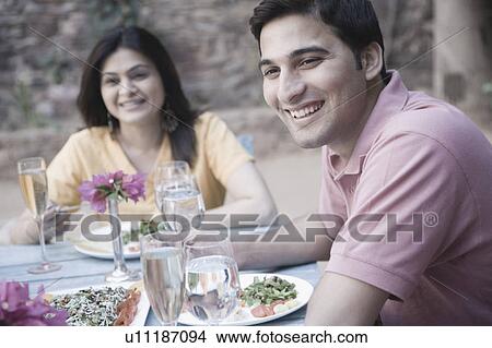 Close-up of a young man sitting with a mid adult woman at a dining table and smiling View Large Photo Image Picture - Close-up of a young man sitting with a mid adult woman at a dining table and smiling. Fotosearch
