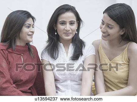 Stock Photo - Close-up of a young woman sitting with two mid adult women and smiling. Fotosearch