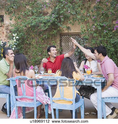 Group of people sitting at a dining table View Large Photo Image Stock Image - Group of people sitting at a dining table. Fotosearch