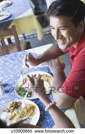 Stock Photography - Mid adult couple sitting in a restaurant and smiling. Fotosearch