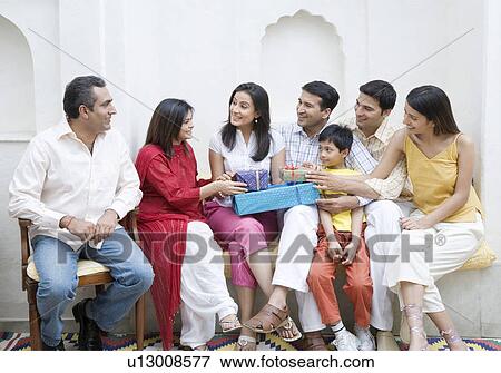 Mid adult women holding gifts and sitting with her family View Large Photo Image Stock Photo - Mid adult women holding gifts and sitting with her family. Fotosearch