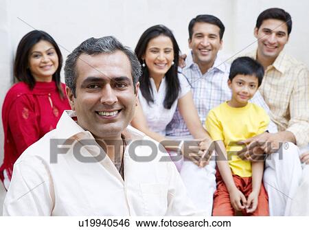 Portrait of a mid adult man smiling with his family smiling in the background View Large Photo Image Stock Photograph - Portrait of a mid adult man smiling with his family smiling in the background. Fotosearch
