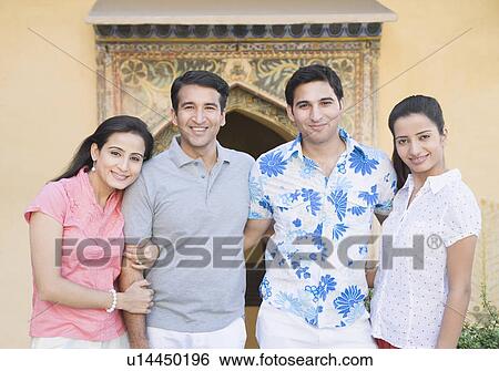 Portrait of a young couple standing with a mid adult couple and smiling View Large Photo Image Stock Photograph - Portrait of a young couple standing with a mid adult couple and smiling. Fotosearch