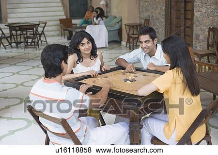 Two young men and two young women playing carom View Large Photo Image Stock Photo - Two young men and two young women playing carom. Fotosearch