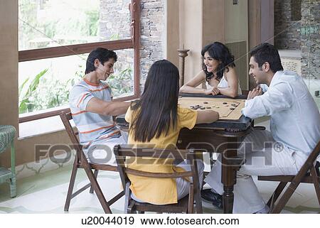 Two young men and two young women playing carom View Large Photo Image Stock Photo - Two young men and two young women playing carom. Fotosearch