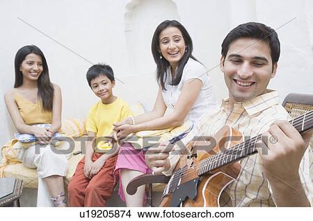 Picture - Young man playing a guitar and smiling. Fotosearch