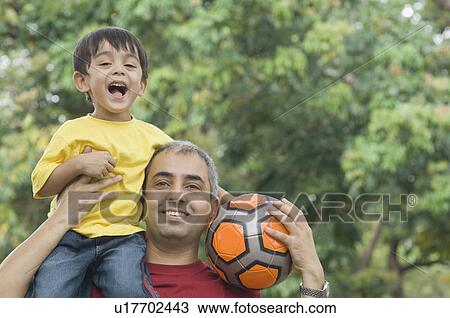 Close-up of a mid adult man carrying his son on his shoulder and holding a soccer ball View Large Photo Image Stock Image - Close-up of a mid adult man carrying his son on his shoulder and holding a soccer ball. Fotosearch