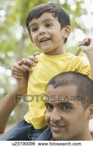 Stock Photograph - Close-up of a young man carrying a boy on his shoulders. Fotosearch