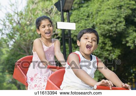 Girl and a boy sitting on a seesaw View Large Photo Image Picture - Girl and a boy sitting on a seesaw. Fotosearch