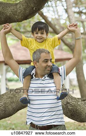 Mid adult man carrying his son on his shoulder View Large Photo Image Stock Photo - Mid adult man carrying his son on his shoulder. Fotosearch
