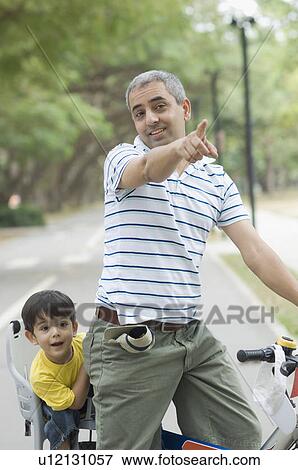 Mid adult man riding a bicycle with his son sitting behind him View Large Photo Image Stock Photo - Mid adult man riding a bicycle with his son sitting behind him . Fotosearch