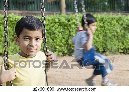 Stock Photo - Portrait of a boy sitting on a swing. Fotosearch